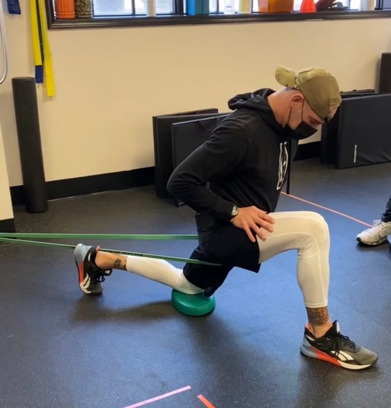 chiropractor helping teach patient how to stretch it band